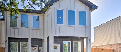 A two-story residential building with a garage, a front door, and a welcome sign.