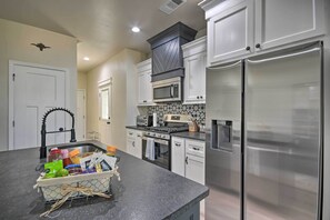 A modern kitchen with stainless steel appliances, white cabinetry, and a black countertop.