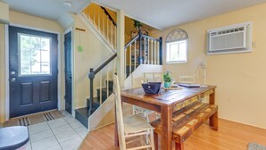 Un comedor con una mesa de madera, sillas, una escalera y una puerta.