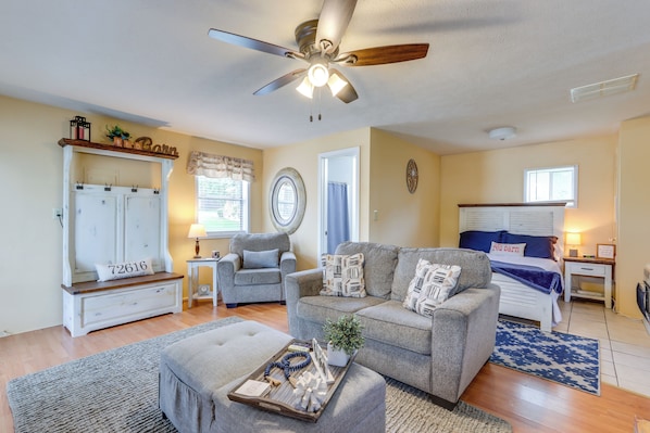 A living room with a ceiling fan, a sofa, a loveseat, a coffee table, and a bed with a headboard. - 12 Mi to Eureka Springs: Charming Studio Retreat (Berryville)