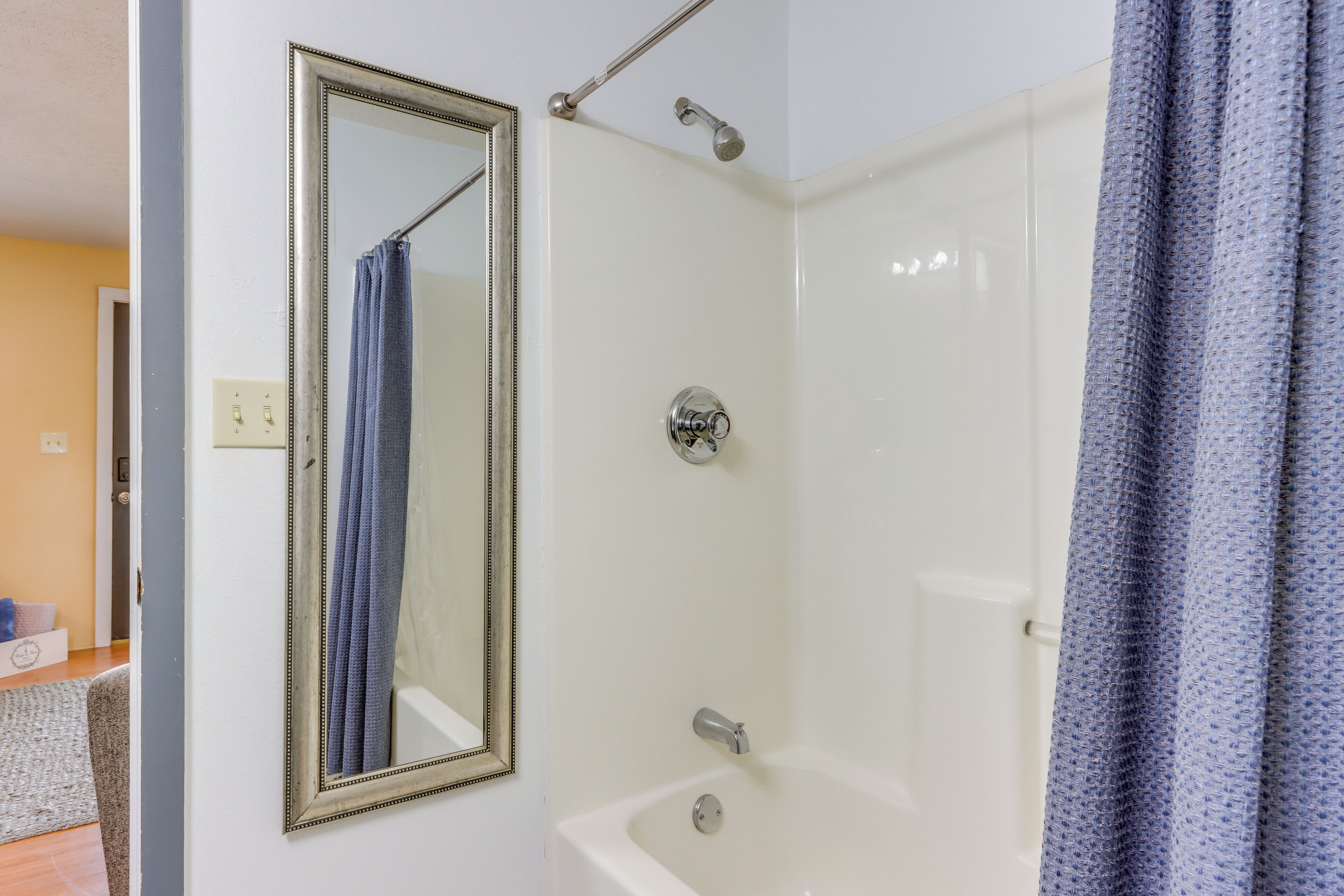 Un baño con bañera, ducha, espejo y toallero.