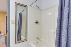 Een badkamer met een bad, een douche, een spiegel en een handdoekhouder.