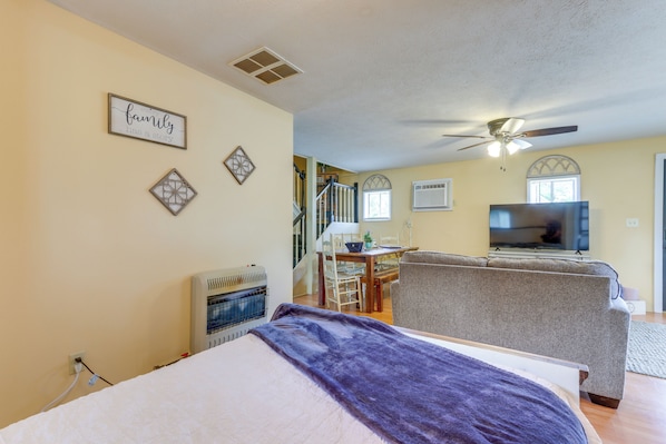 Ein Schlafzimmer mit Bett, Deckenventilator, Fernseher und einer Treppe zu einem weiteren Raum.