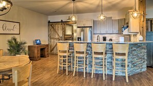 A kitchen with a central island, bar stools, wooden cabinets, and pendant lighting. - Beaver Lake Retreat w/ Lake Access & Fire Pit! (Garfield)