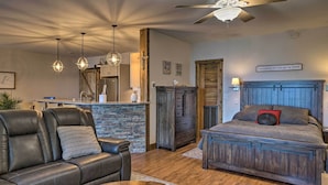 A cozy bedroom with a bed, a leather sofa, and a stone fireplace. - Beaver Lake Retreat w/ Lake Access & Fire Pit! (Garfield)