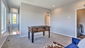 A room with a foosball table, a blue sofa, and a fur rug.
