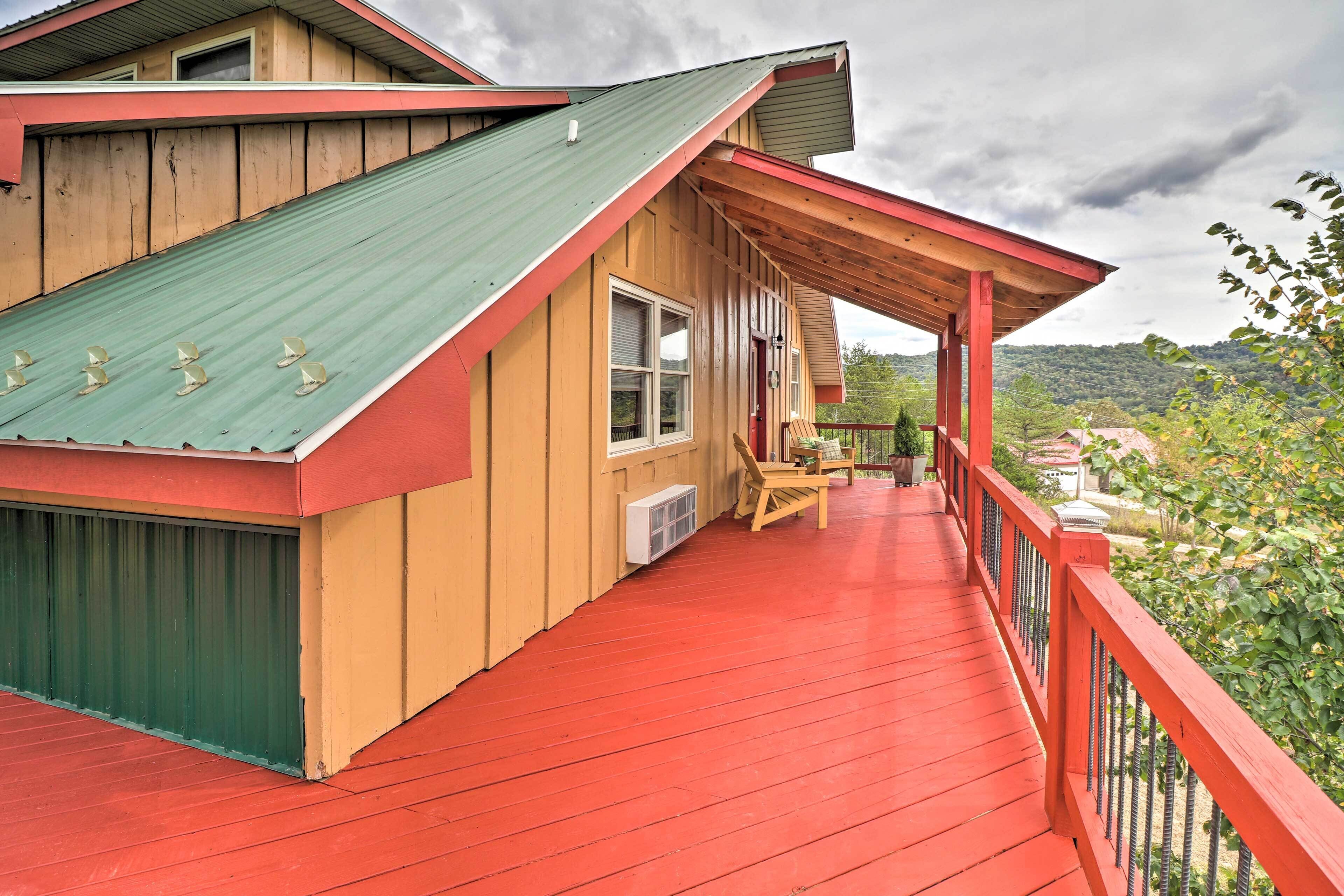A wooden house with a red deck and a green roof.