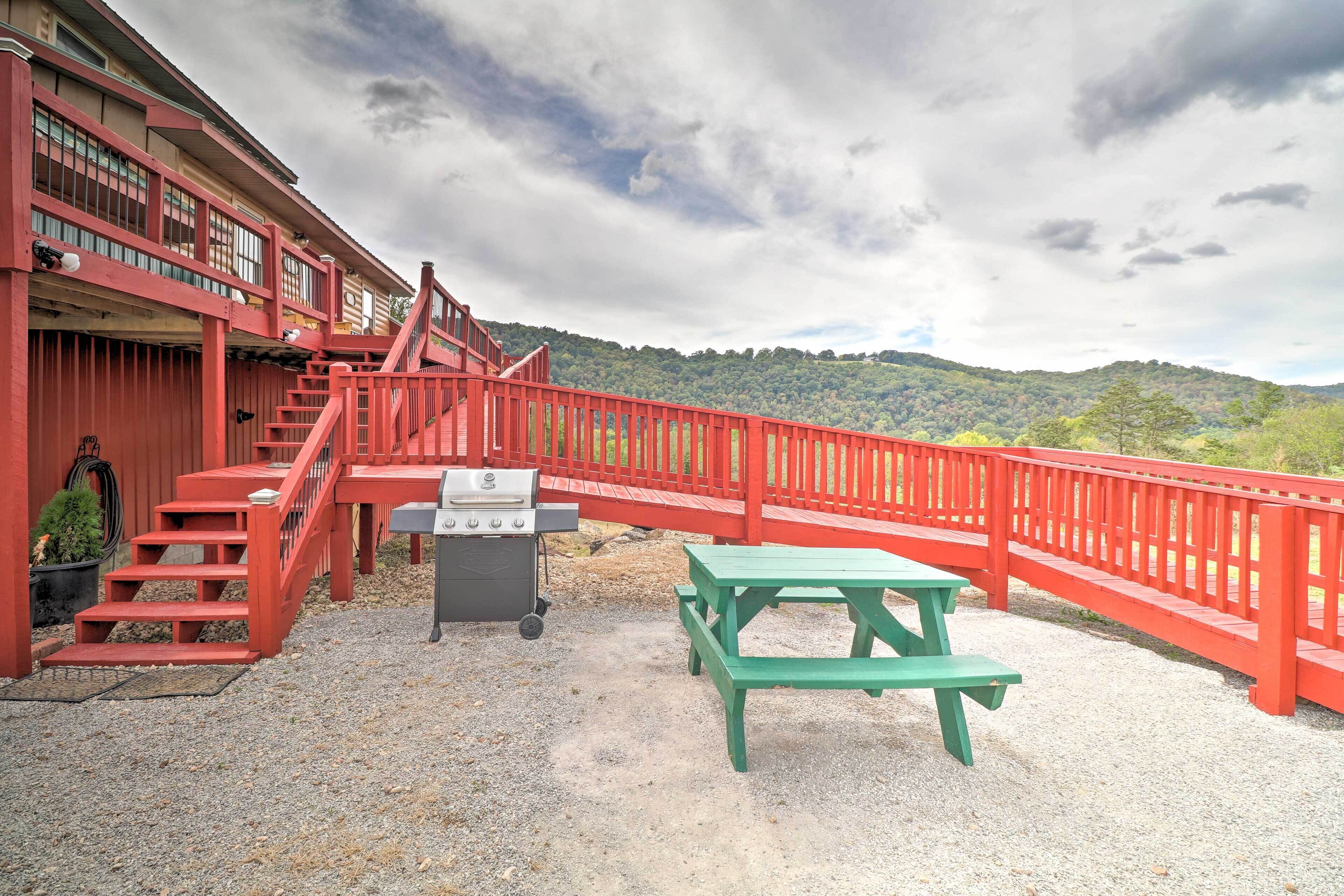 A red building with a staircase, a barbecue grill, and a picnic table.