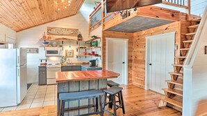 A cozy cabin-style kitchen with wooden floors, a central island, and a staircase leading to a loft. - Mountain View Escape - 1 Mile to White River! (Mountain View)