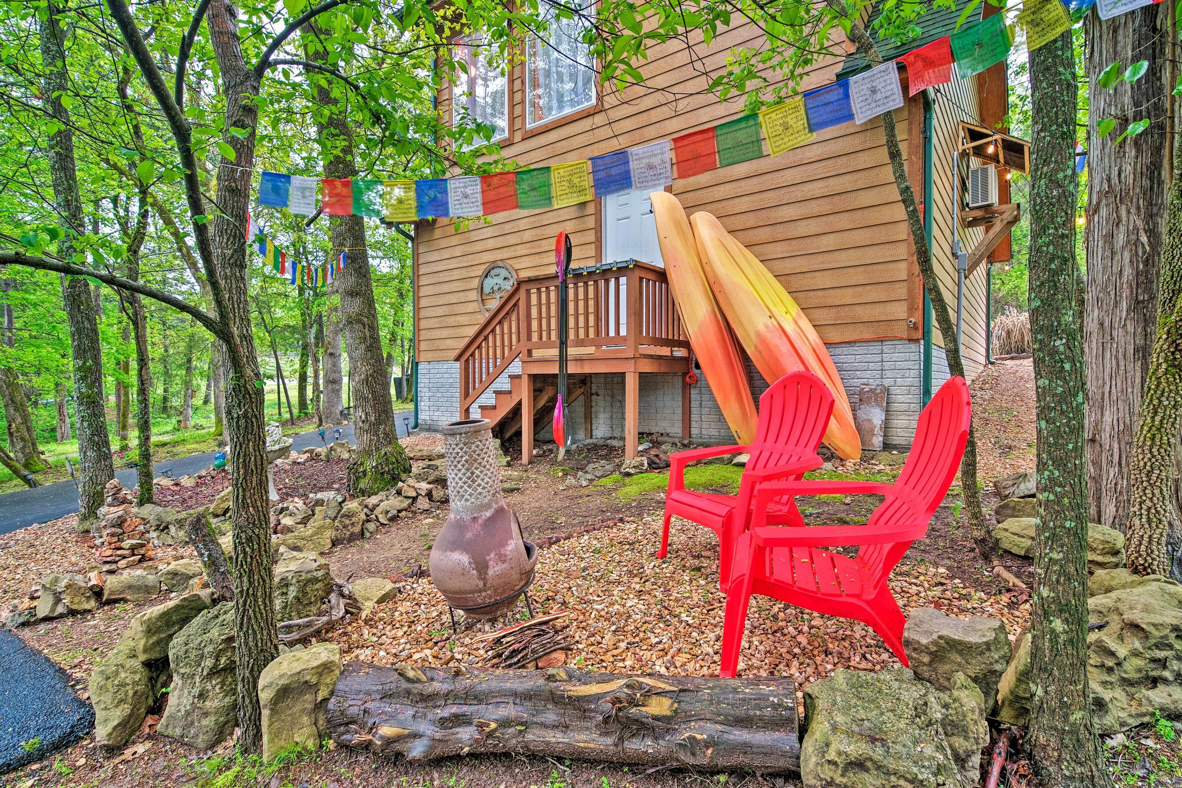 A wooden cabin with a deck, surrounded by trees and rocks.