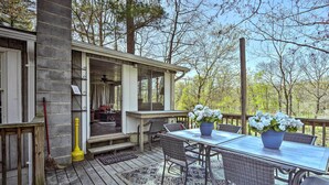 A covered outdoor patio with a table and chairs, a stone pillar, and a view of trees. - Cozy Cabin With Sunroom & Cacapon River Access! (Capon Bridge)
