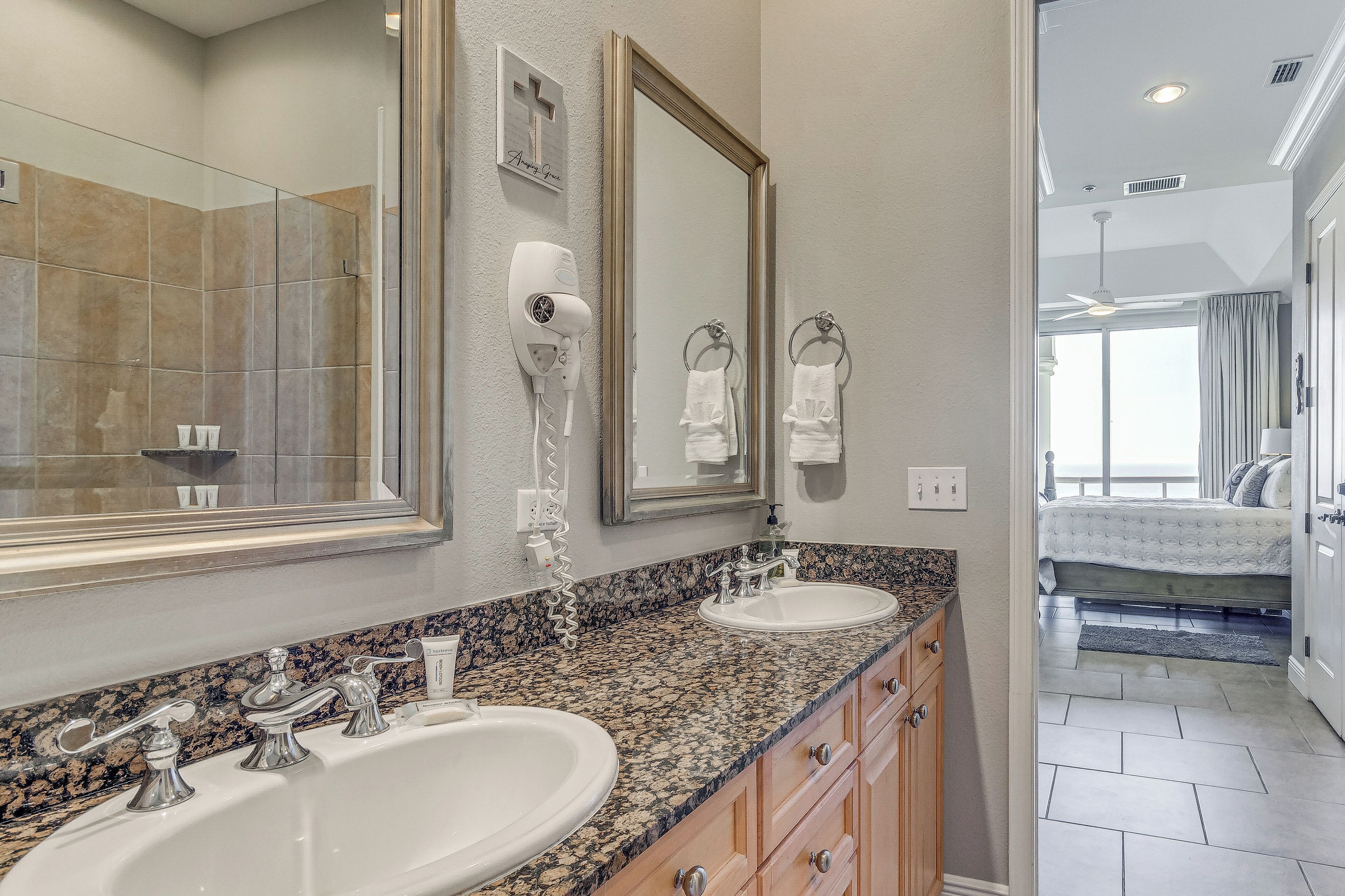 A bathroom with two sinks, a hairdryer, and a large mirror.