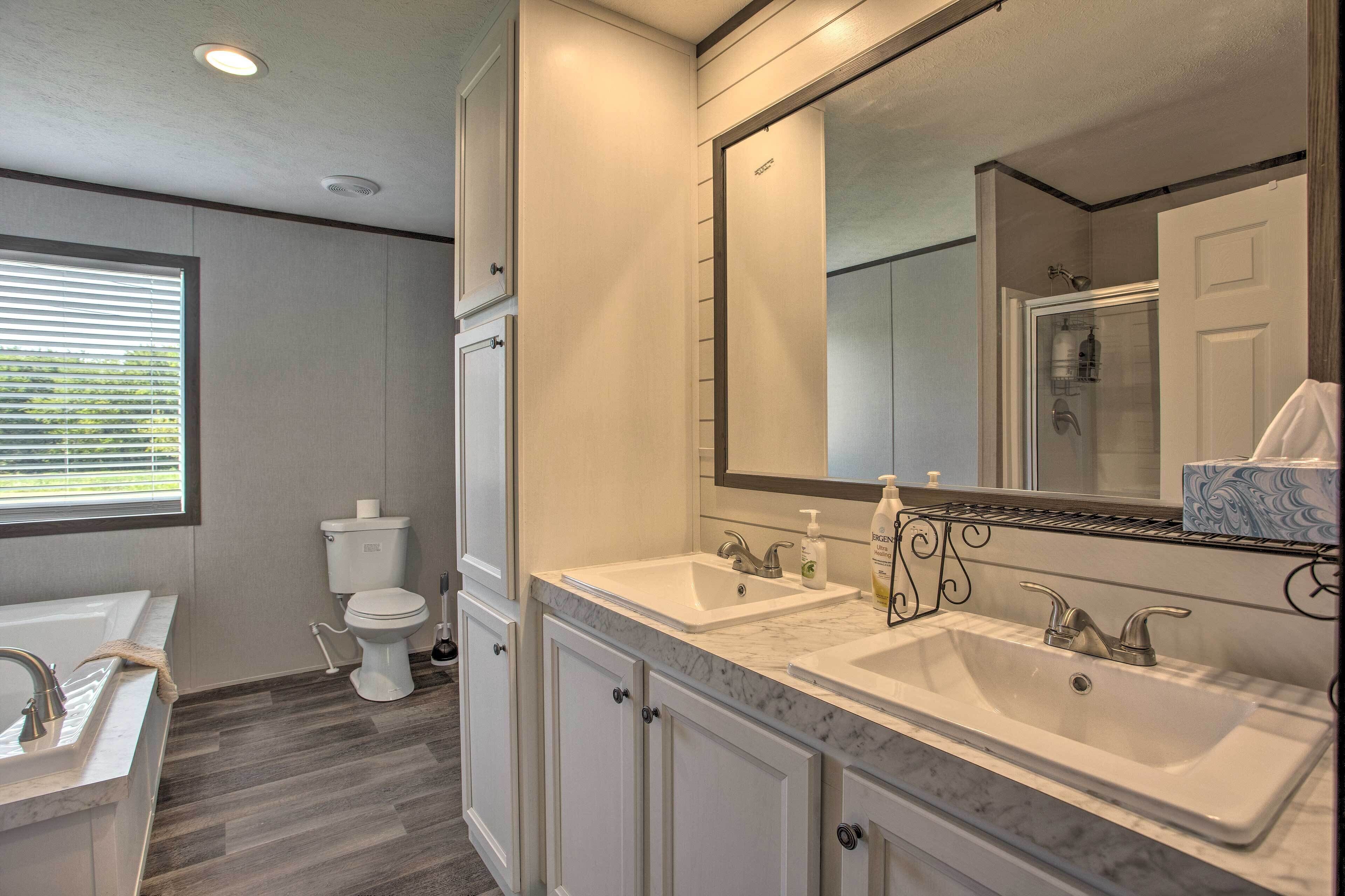 A bathroom with two sinks, a toilet, and a large mirror.