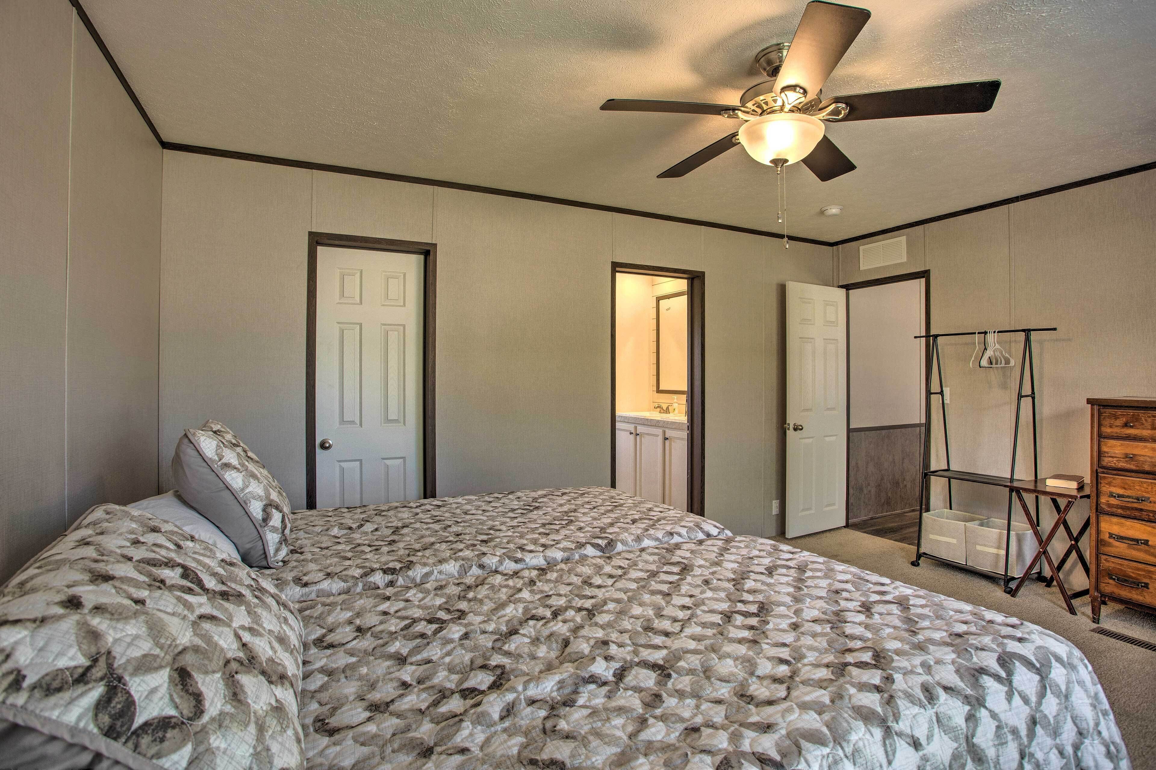 A bedroom with a bed, a ceiling fan, a dresser, and a walk-in closet.
