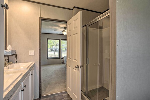A bathroom with a glass shower enclosure, a white sink, and a mirror.