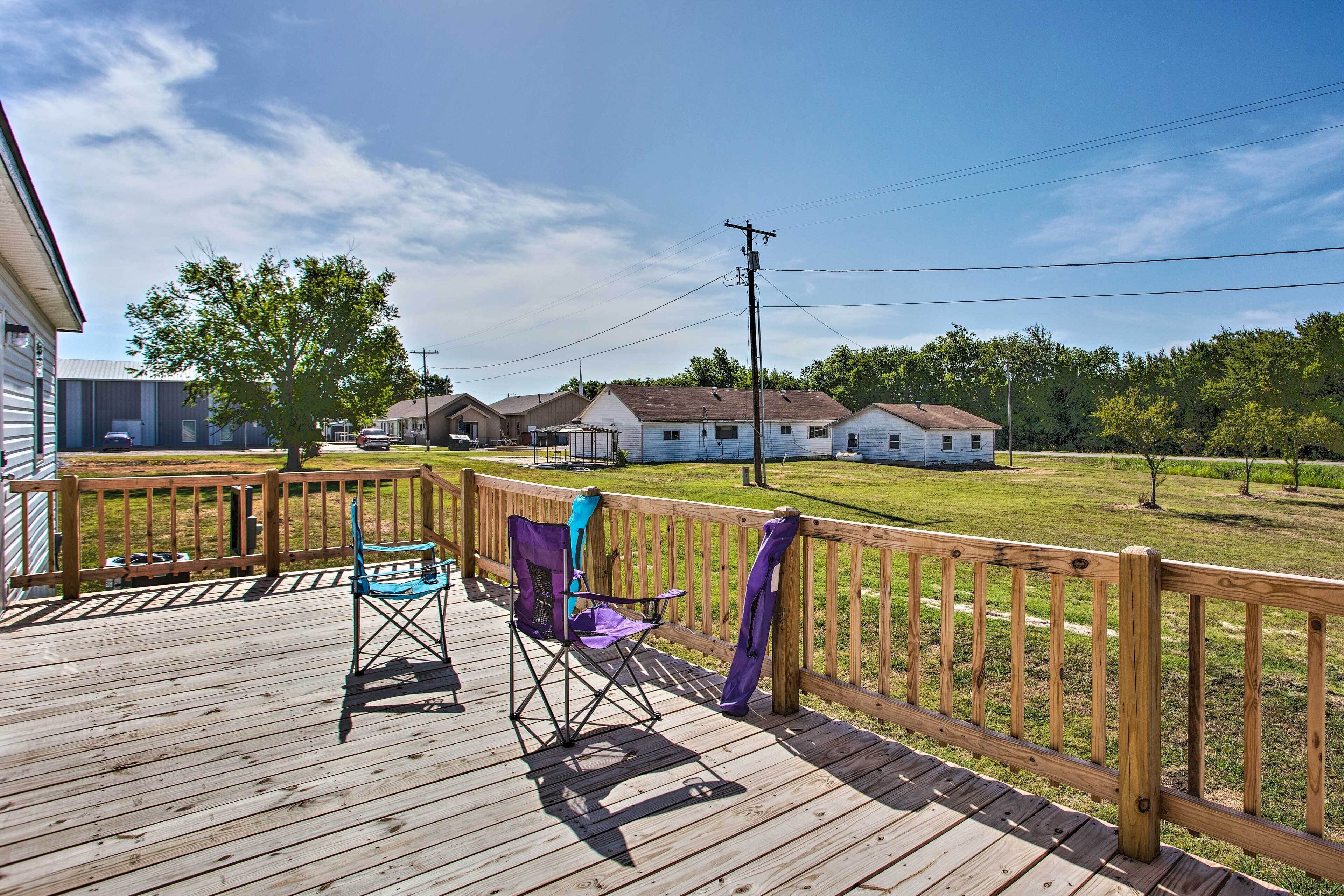 Une terrasse en bois offrant une vue sur des maisons et une zone herbeuse.