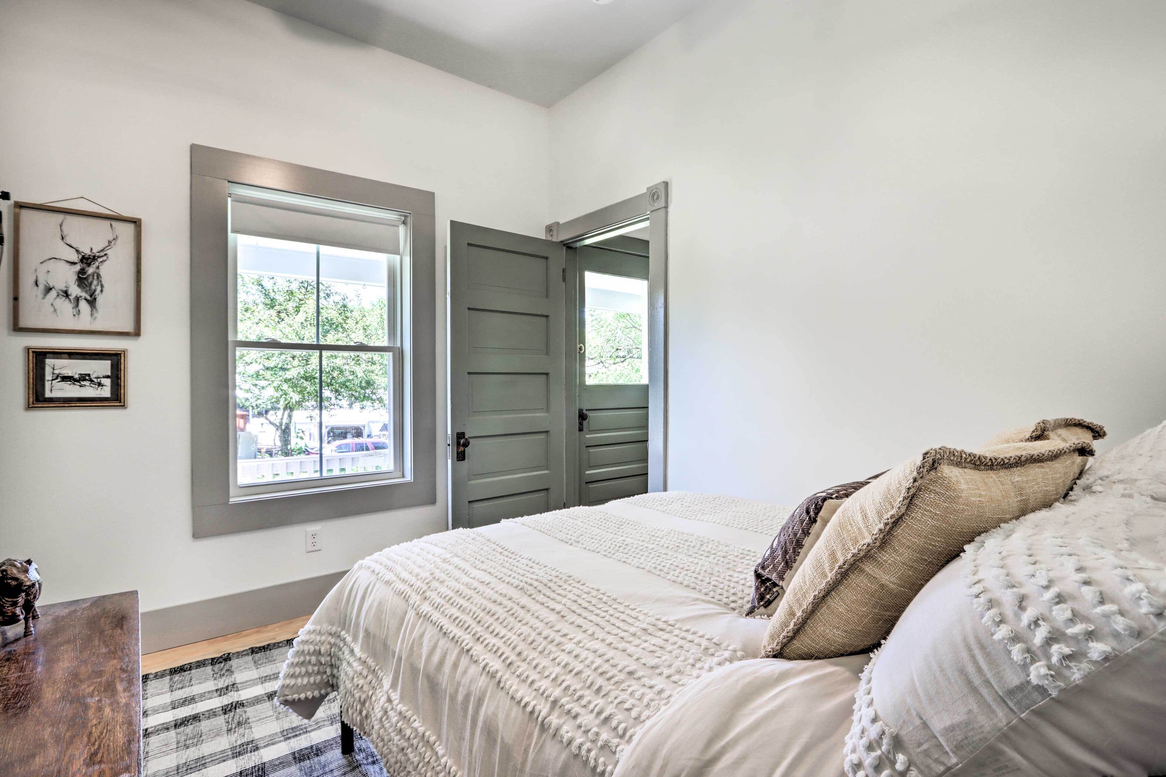 A bedroom with a large bed, a window, and a door.