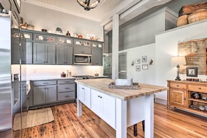 A modern kitchen with grey cabinets, a wooden island, and a coffee bar area.