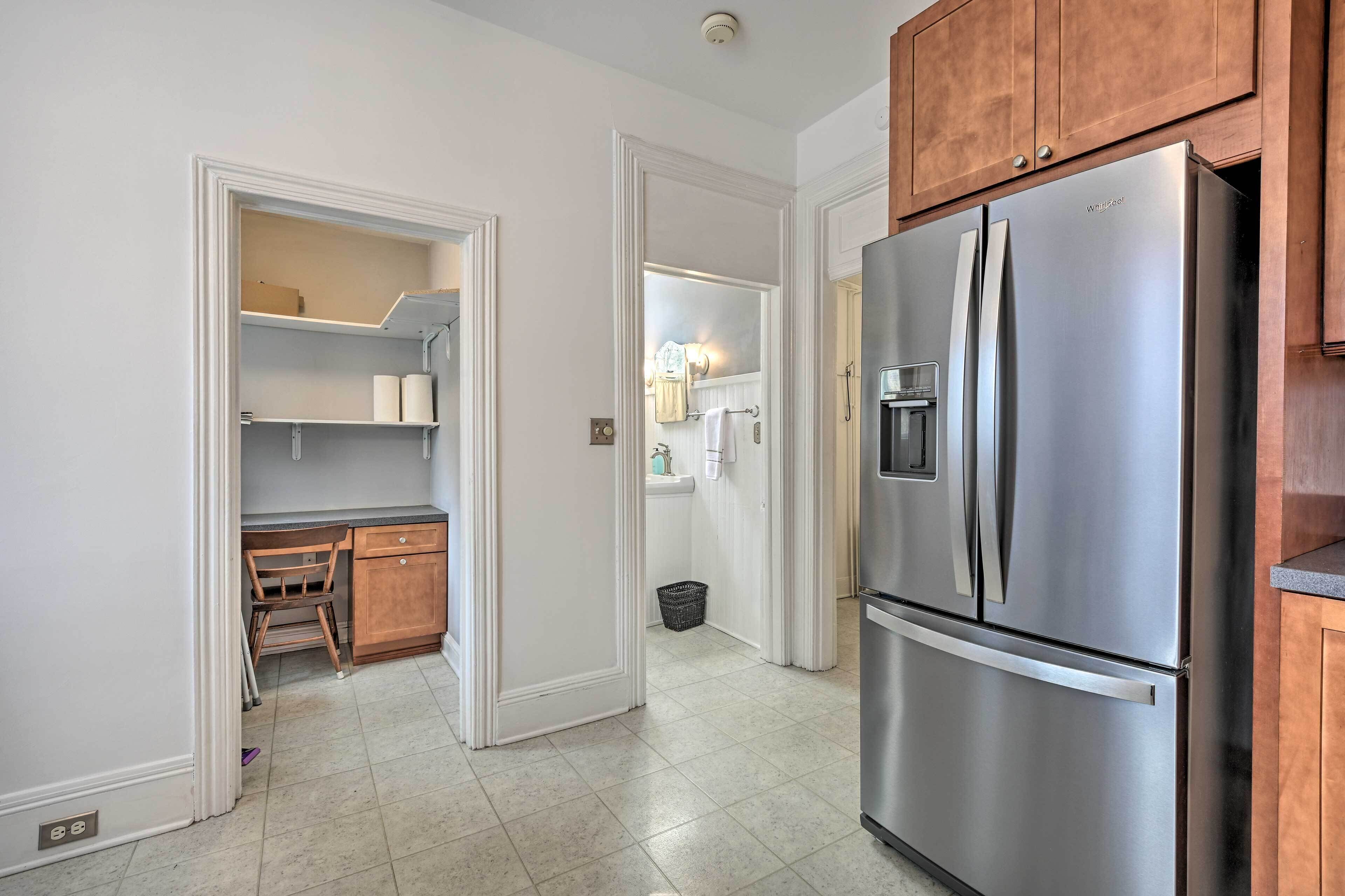 A kitchen with a stainless steel refrigerator, wooden cabinets, and a tiled floor.