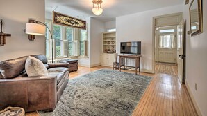 A living room with a brown leather sofa, a large rug, a television, and a decorative wall piece. - Spacious Getaway: 7 Mi to Whitetail Slopes! (Mercersburg)