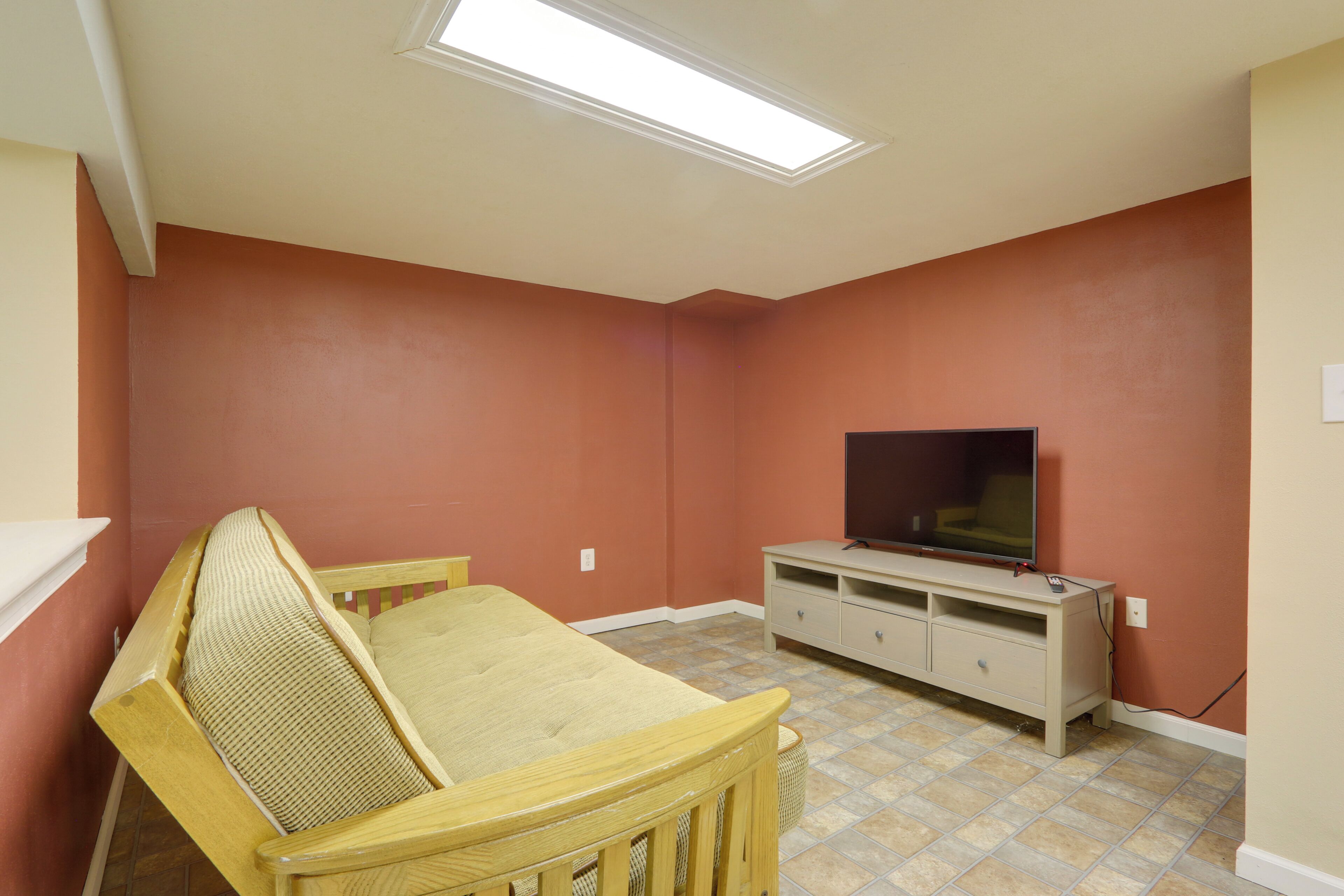Una habitación con una cama, un televisor sobre un mueble bajo y una lámpara en el techo.