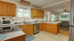 A modern kitchen with wooden cabinets, a dishwasher, a microwave, and a coffee maker. - Harpers Ferry Cabin - Walk to Private Lake! (Harpers Ferry)