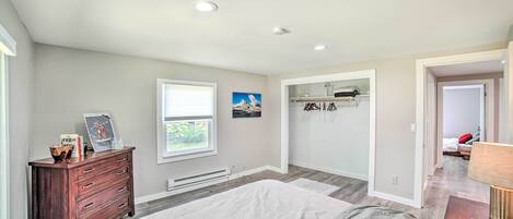 A bedroom with a bed, dresser, window, and built-in shelving.