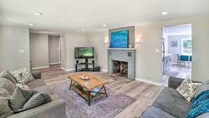 A living room with a fireplace, a television, and a dining area visible in the background.