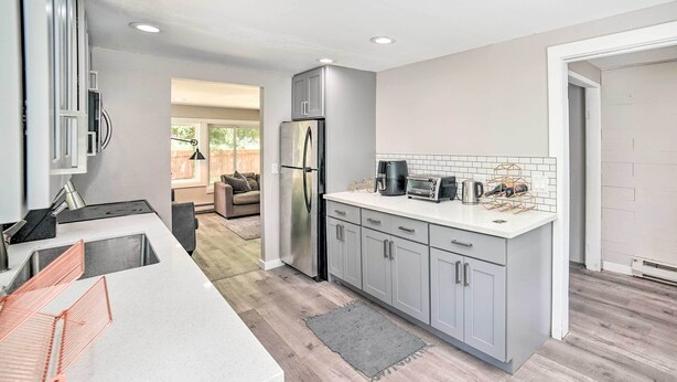 A modern kitchen with stainless steel appliances, a white countertop, and grey cabinetry.