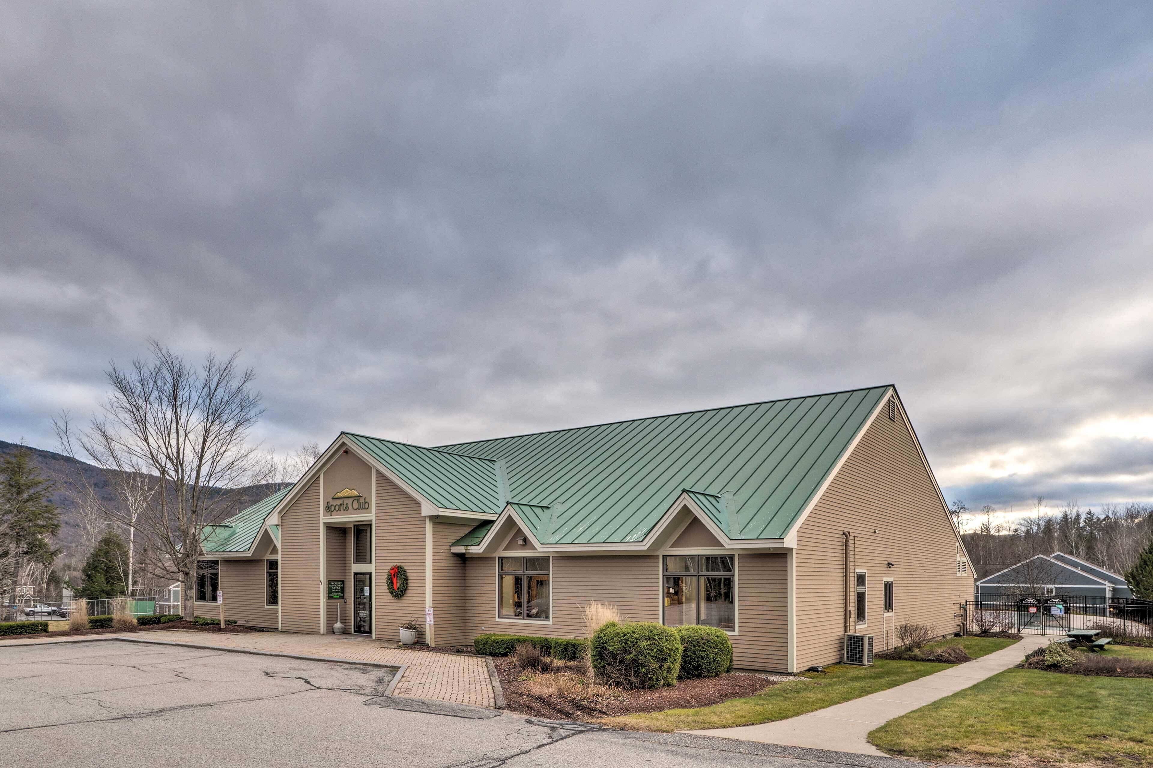 A building with a green roof, a sign reading "Sports Club," and a paved entrance area.