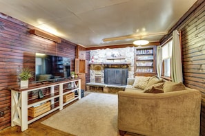 A cozy living room with a fireplace, a television, and a bookshelf.