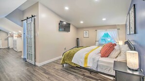 A bedroom with a bed, bedside table, lamp, and a window with curtains.