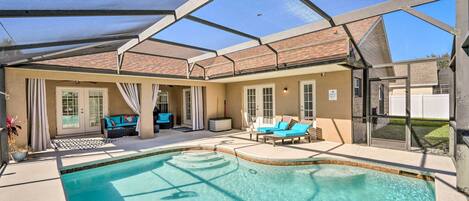 A swimming pool with a covered patio area, including lounge chairs and a seating area.