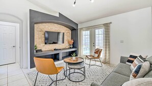 A modern living room with a fireplace, a sofa, a coffee table, and a TV mounted on the wall. - Clermont Vacation Rental w/ Pool: 11 Mi to Disney (Clermont)