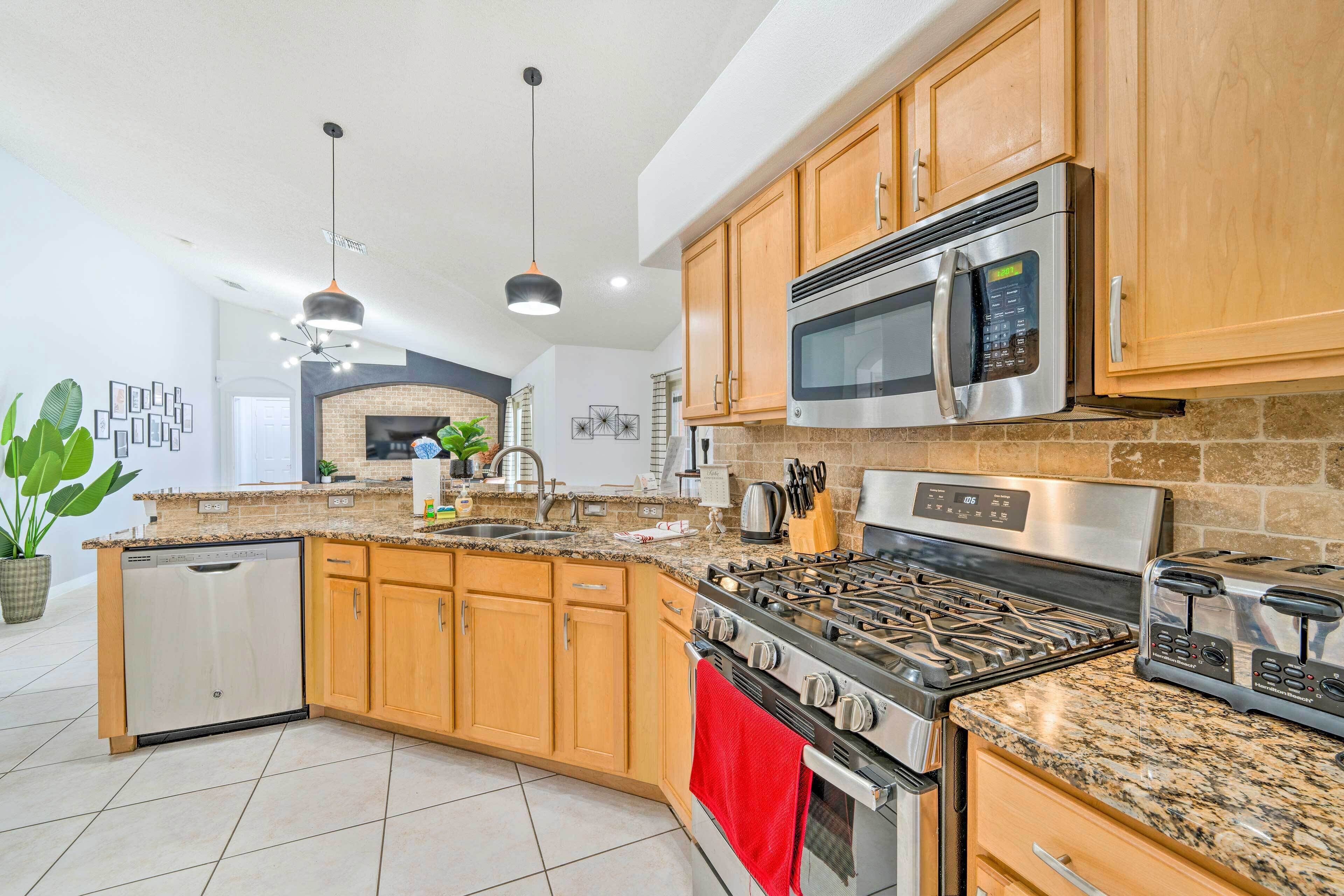 A modern kitchen with granite countertops, stainless steel appliances, wooden cabinets, and a built-in oven.