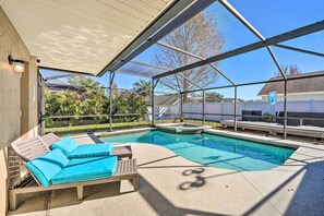 A covered outdoor swimming pool with lounge chairs and a hot tub.