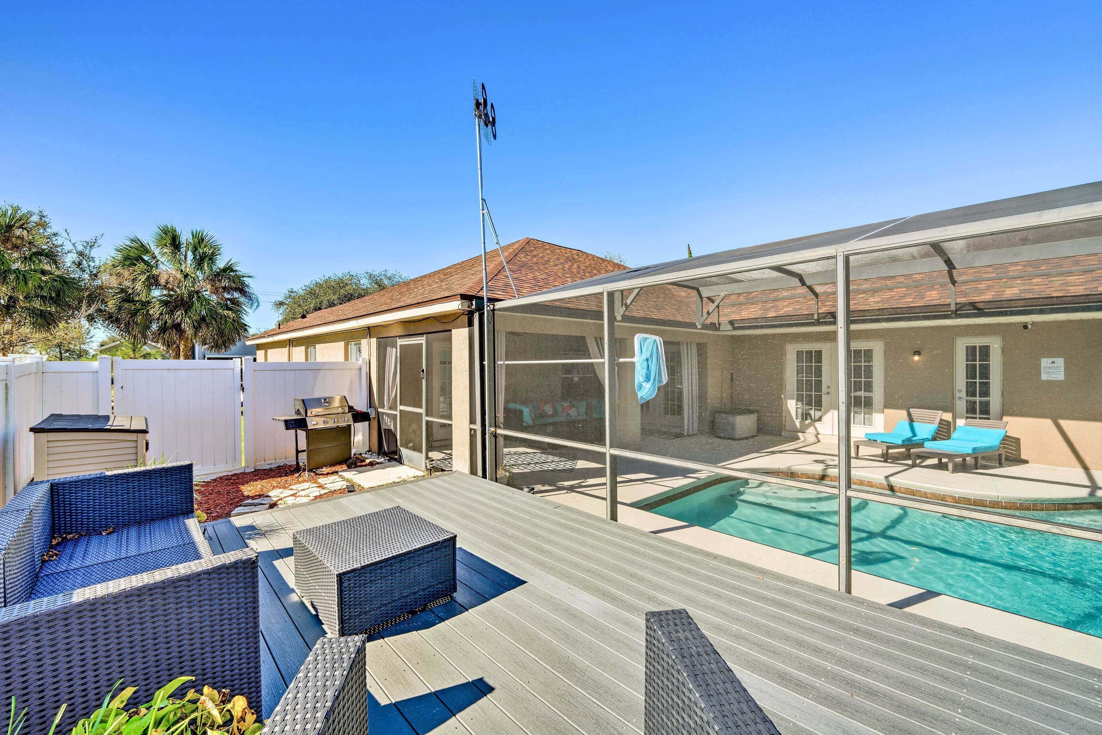 A backyard with a swimming pool, outdoor seating, and a covered patio area.