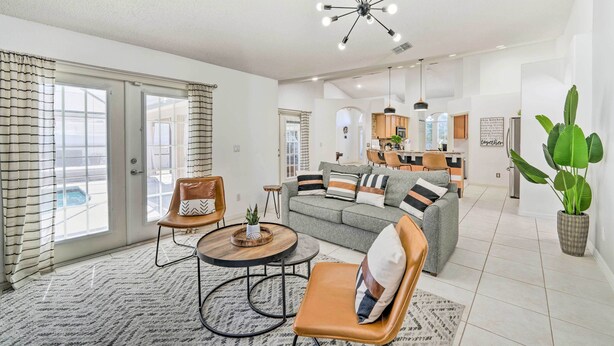 A spacious living area with a grey sofa, brown leather chairs, a round coffee table, and a modern chandelier. - Clermont Vacation Rental w/ Pool: 11 Mi to Disney (Clermont)
