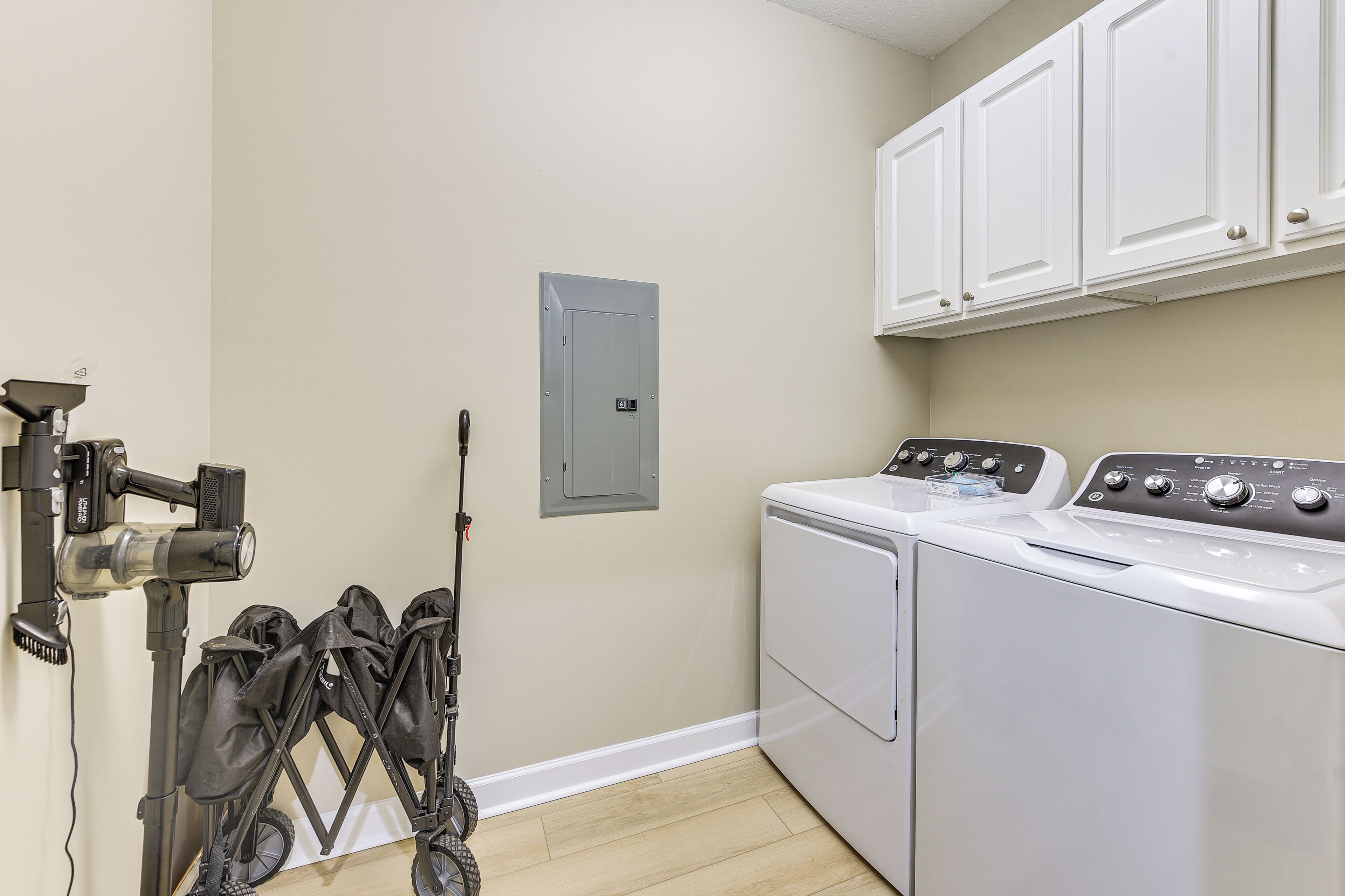 A laundry room with a washing machine, dryer, and a wall-mounted utility box.