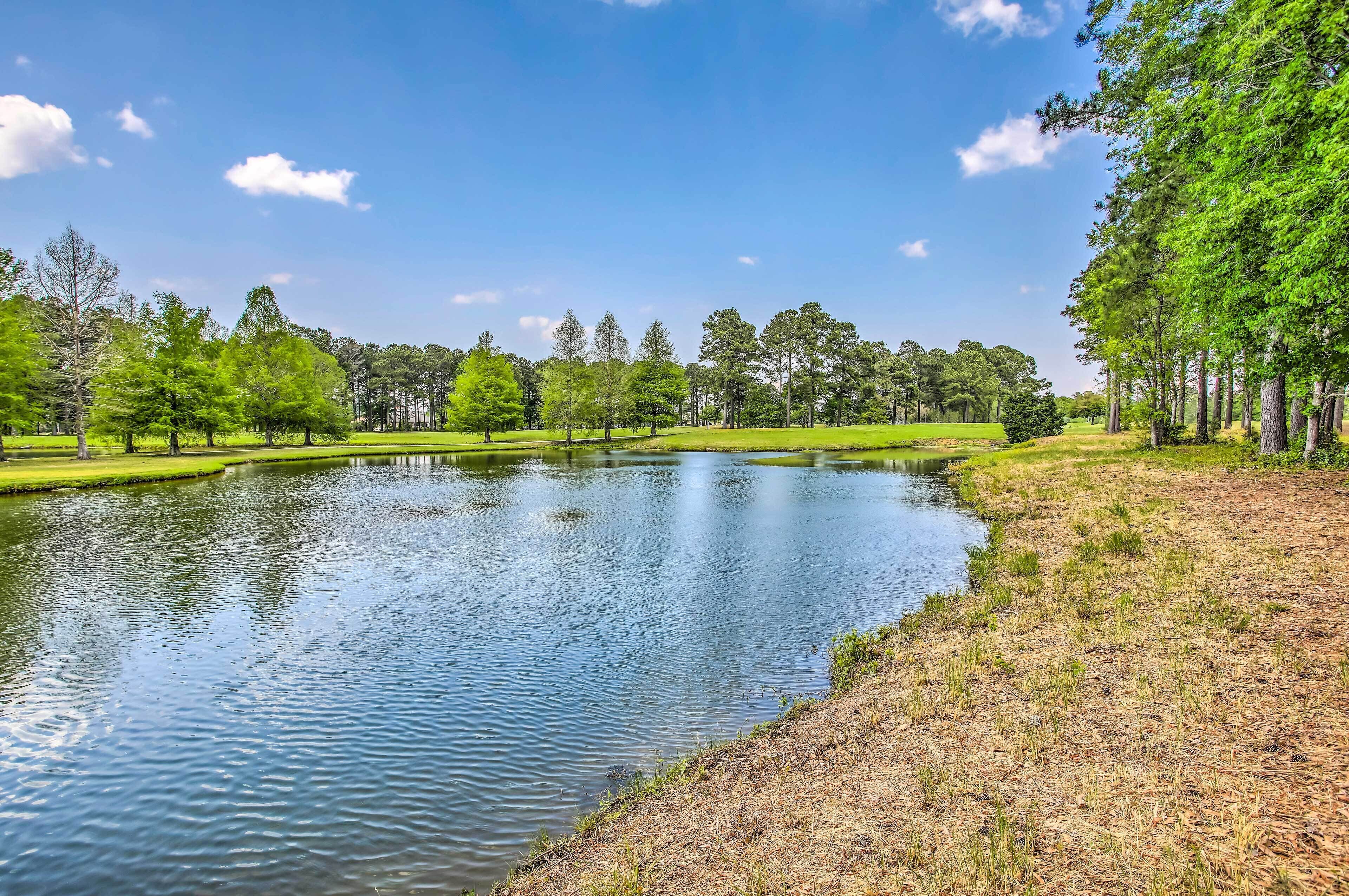 A serene lake surrounded by trees and grassy areas.