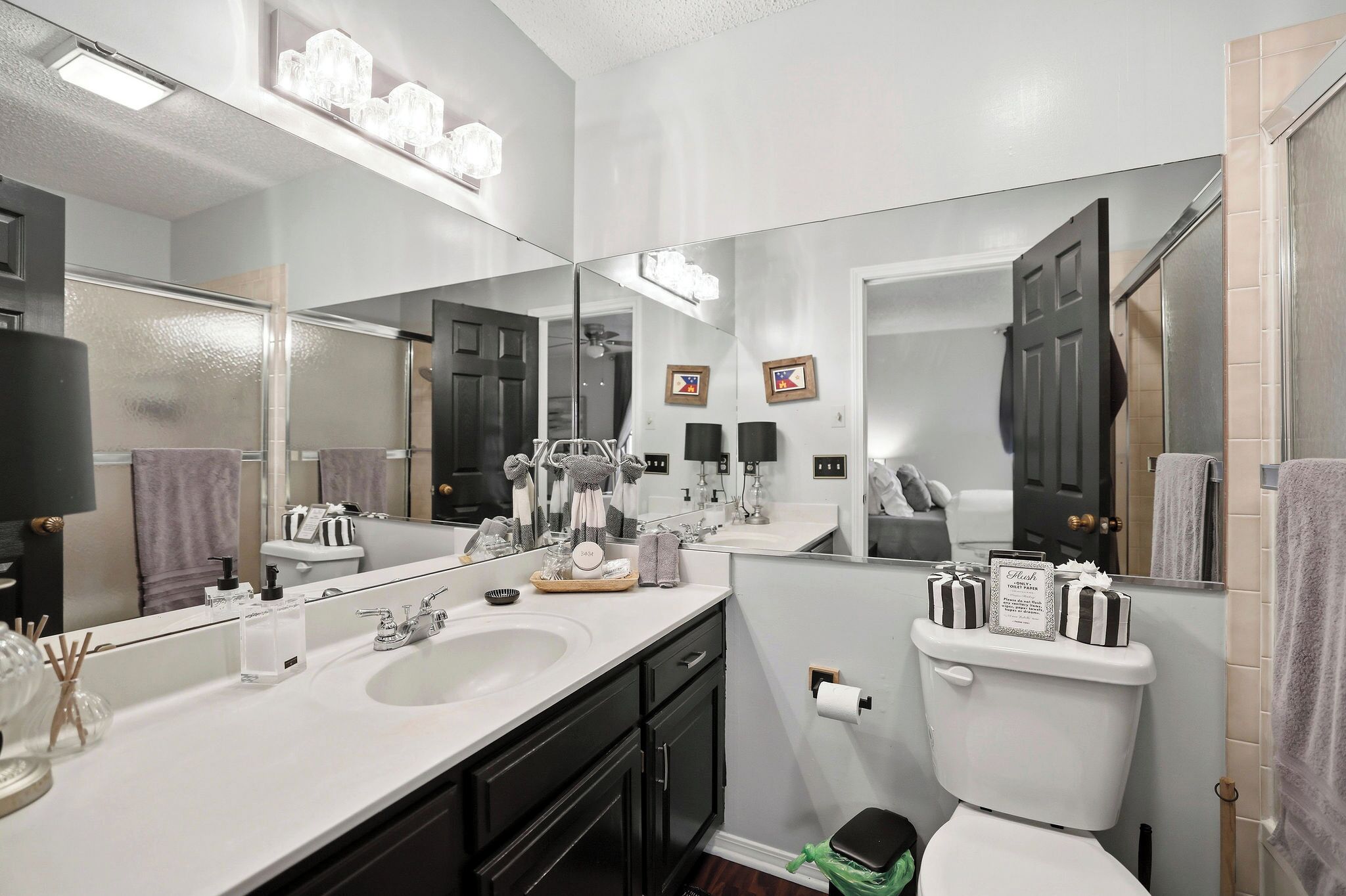 Une salle de bain moderne avec un grand miroir, deux vasques et des toilettes.