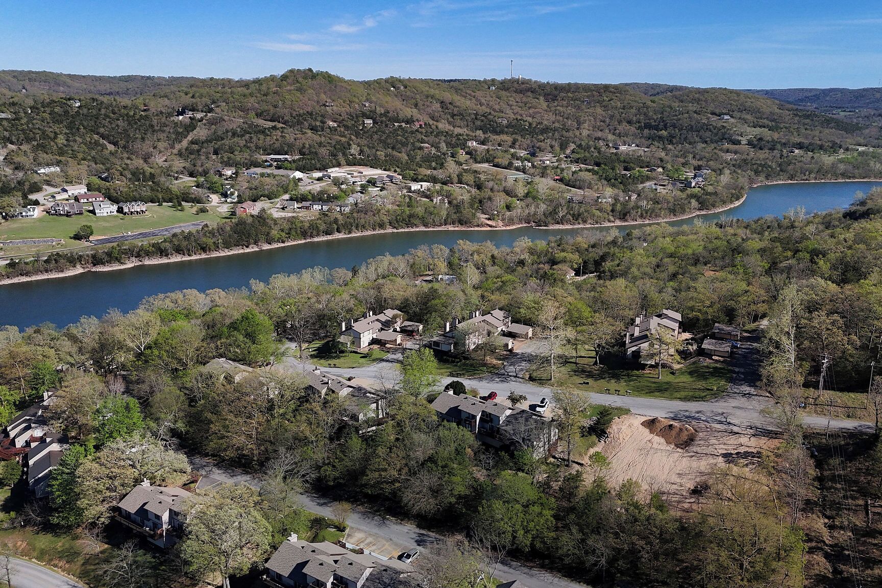 A residential area with houses, a lake, and hilly terrain.
