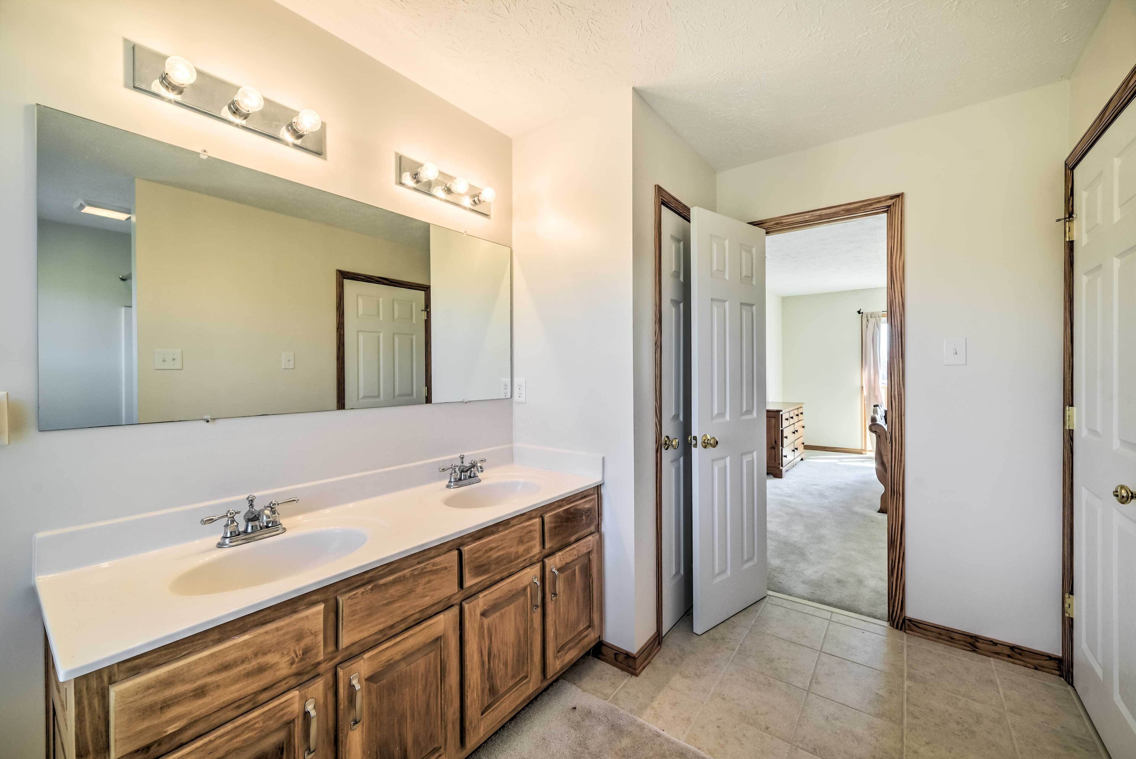 A bathroom with two sinks, a large mirror, and wooden cabinets.