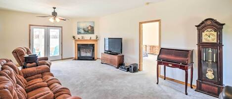 A living room with a large sectional sofa, a fireplace, a television, a piano, and a grandfather clock.