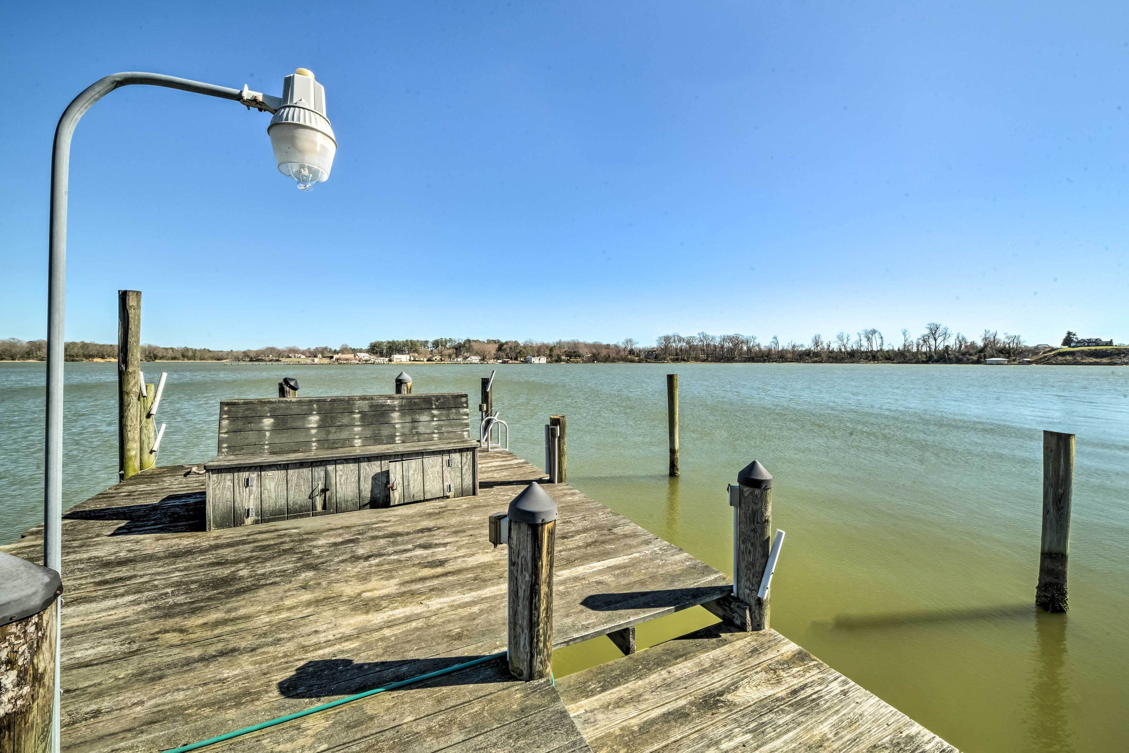 Une jetée en bois s’étendant sur une étendue d’eau, avec un lampadaire et des bancs.