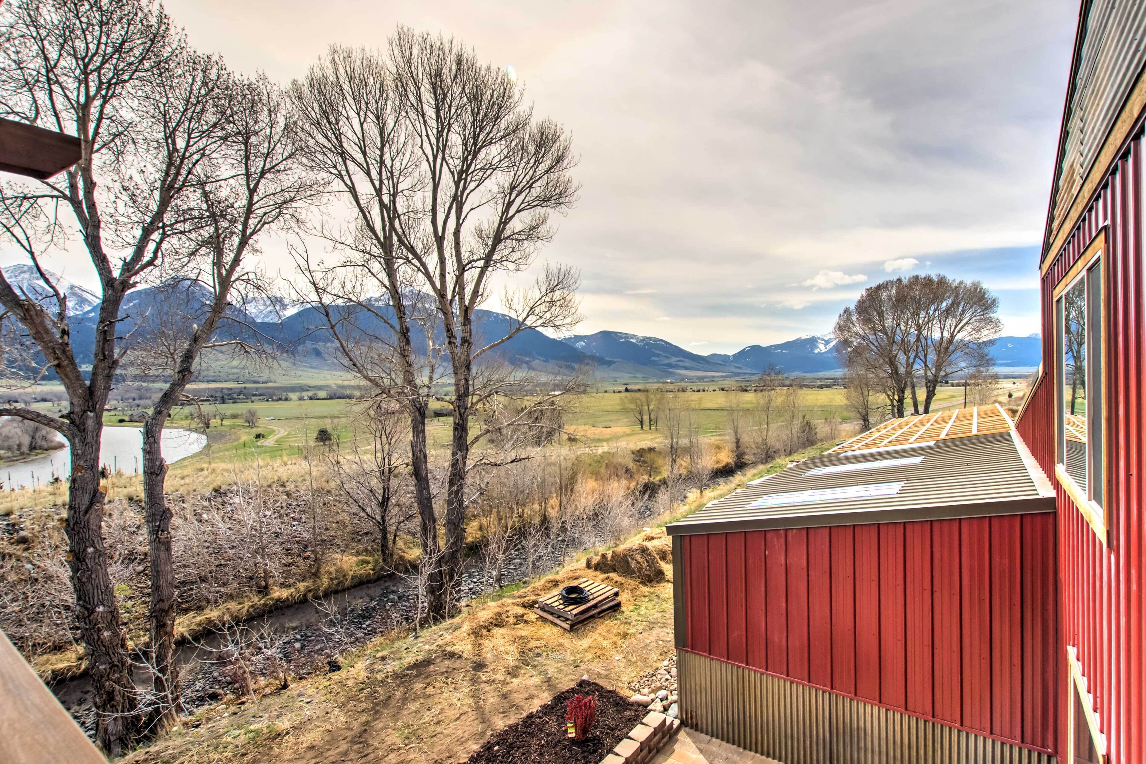 A red building with a view of mountains and a river.