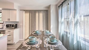 A modern kitchen with white cabinets, a microwave, and a dining area with a table set for four. - 5 Mi to UT: Quiet Toledo Duplex Near Parks! (Toledo)