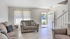 A spacious living room with a beige sofa set, a patterned throw pillow, and a large window with curtains. - 5 Mi to UT: Quiet Toledo Duplex Near Parks! (Toledo)