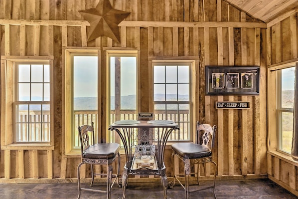 A rustic wooden room with a star on the ceiling, two windows with a view, a table with chairs, and a sign that says "EAT - SLEEP - FISH". - Peaceful Mountain Air Getaway w/ Fire Pit! (Mountain View)