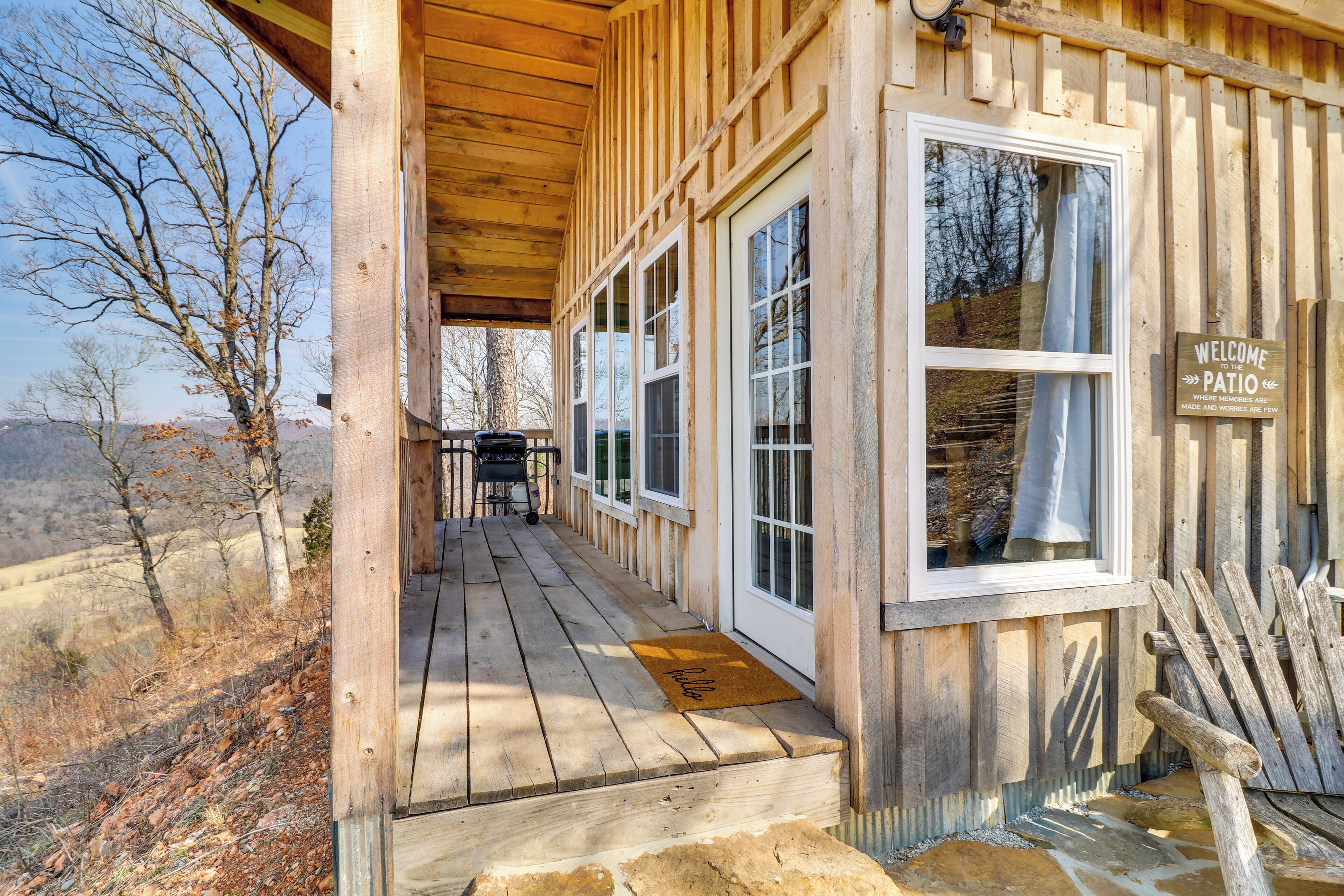 A wooden cabin with a porch, large windows, and a welcome sign.
